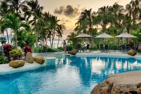 Whitsunday Apartments pool area with palm trees and sun loungers